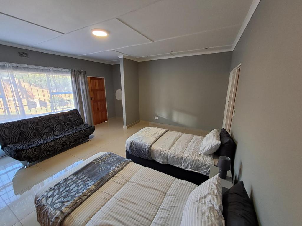 a small room with two beds and a couch at Rocky Hills Guesthouse in Piet Retief