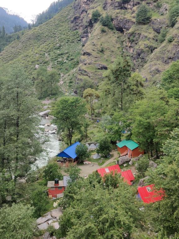 a view of a mountain with tents and a river at Last Stop Riverside wooden Huts, Camps & Dorms in Manāli