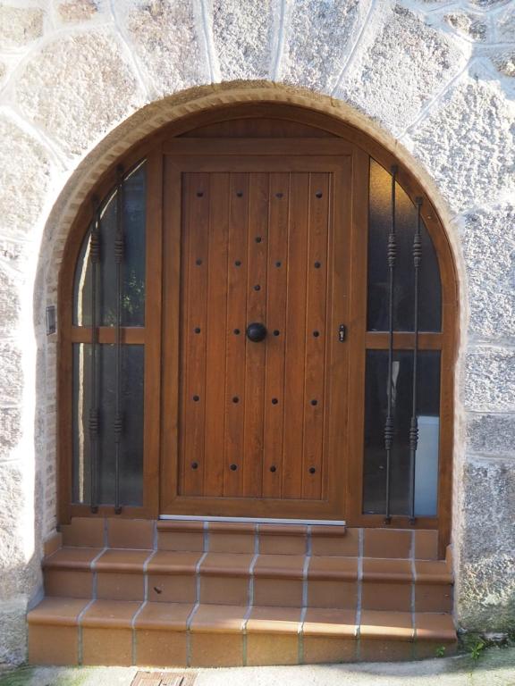 an arched wooden door in a stone building at Casa Jacaranda in Arenas de San Pedro