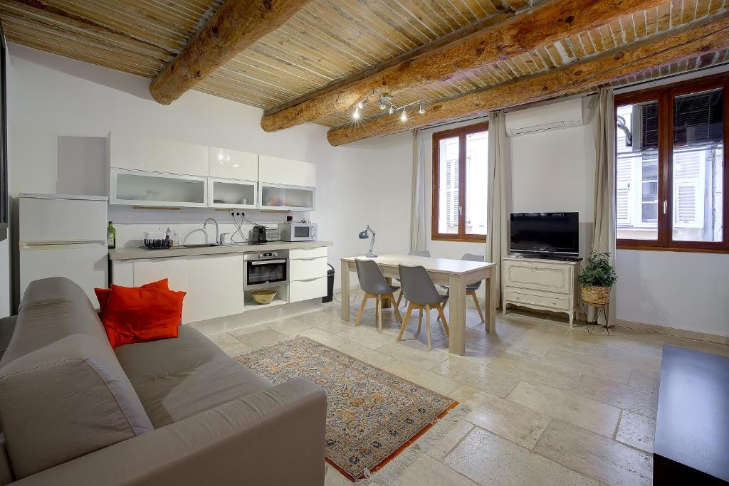 ein Wohnzimmer mit einem Sofa und eine Küche mit einem Tisch in der Unterkunft Le Pairou in Nizza
