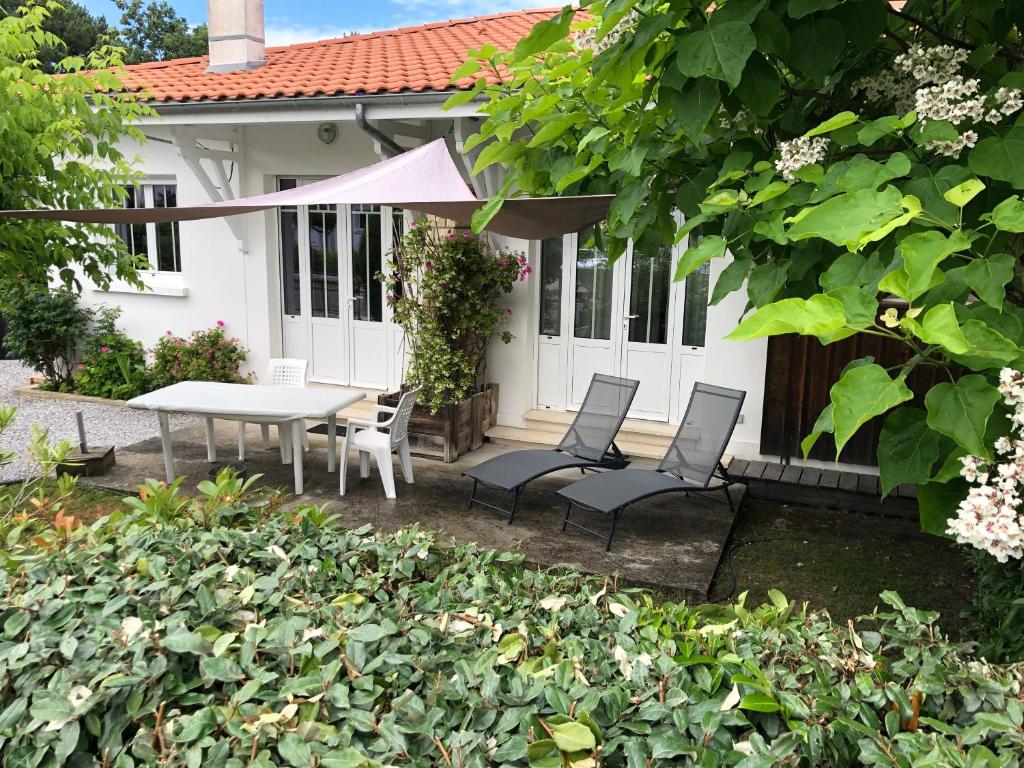 un patio avec une table et des chaises devant une maison dans l'établissement vacances-esprit-cabanes, à Andernos-les-Bains