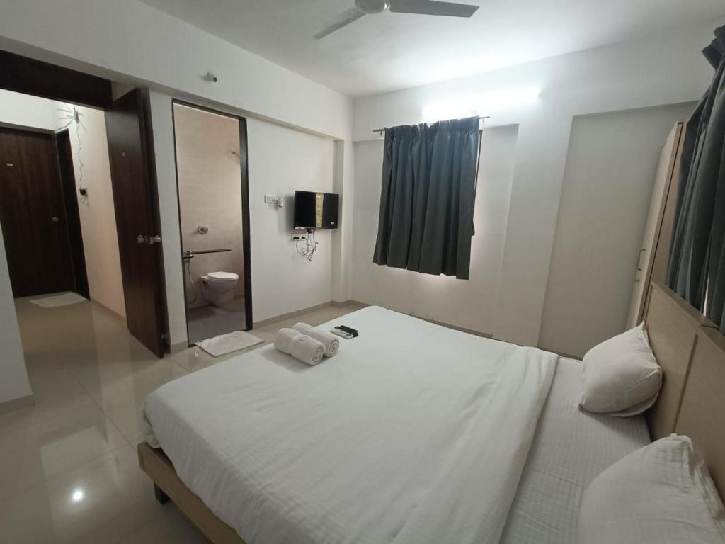 a bedroom with a large white bed and a bathroom at Ornate Service Apartments in Pune