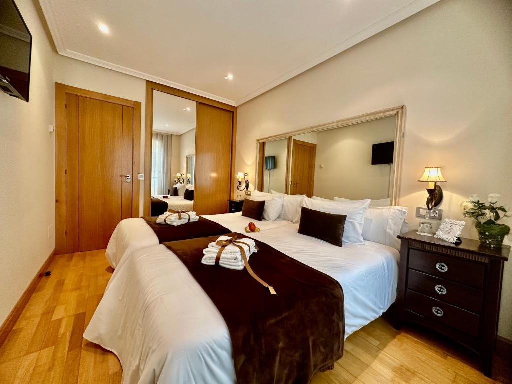 Habitación de hotel con 2 camas y espejo en CLAREN'S GUESTHOUSE en Cangas del Narcea