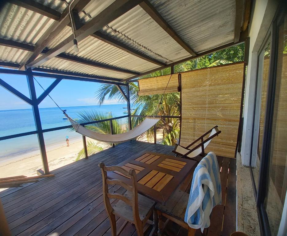 um alpendre com uma rede de descanso, uma mesa e cadeiras em Hôtel chez Pat em Nosy Be