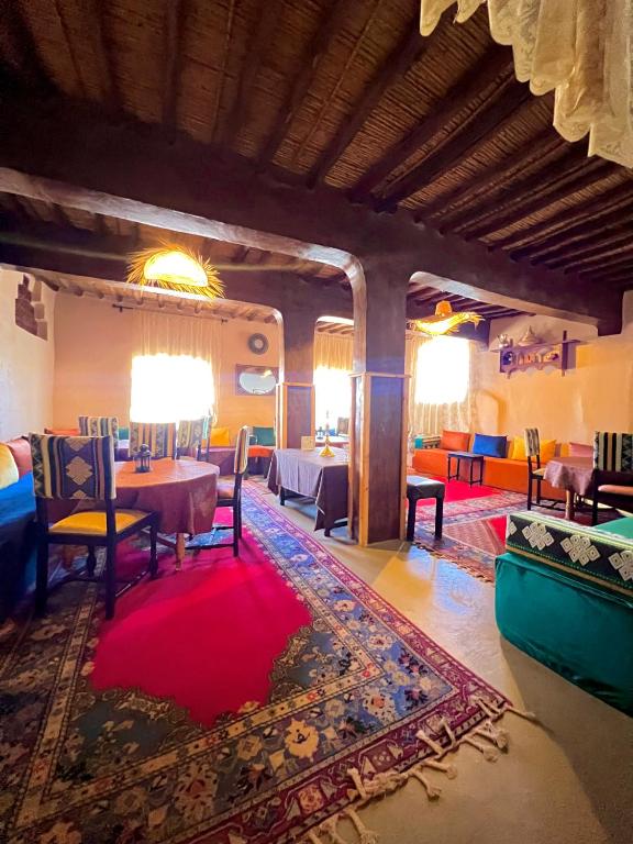 a dining room with a table and chairs and a red rug at Kasbah El Hajja in Aït Benhaddou