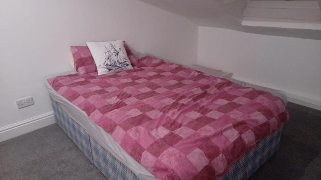 a bed with a pink comforter in a room at Twin room in Hoylake - 500 metres from Royal Liverpool Golf Course in Hoylake