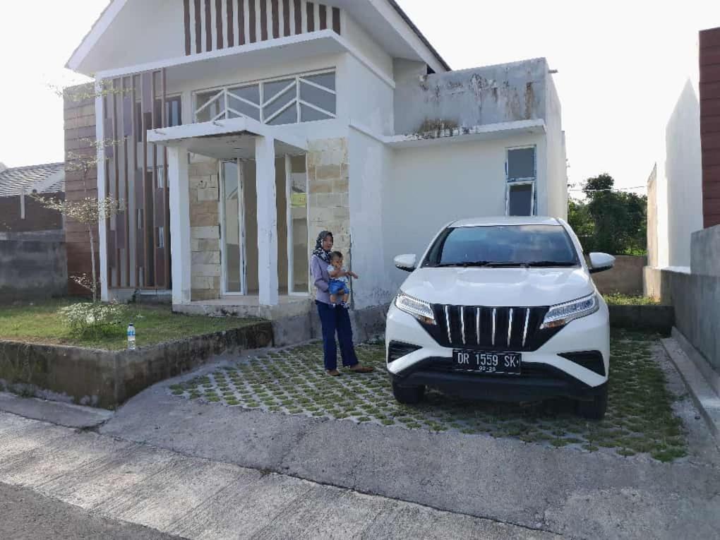 a woman standing next to a white car in front of a house at Muja house villa in Praya