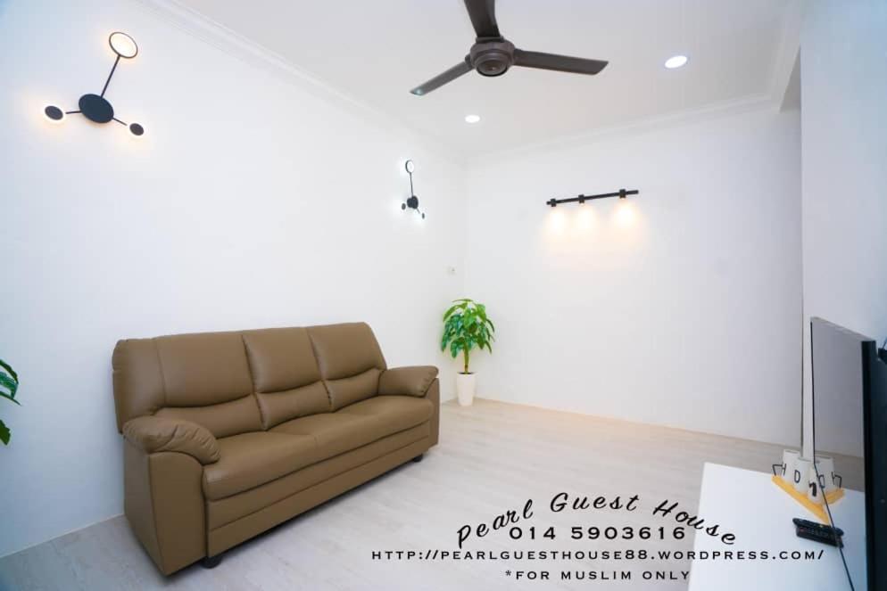 a living room with a couch and a ceiling fan at Pearl Guest House in Kertih