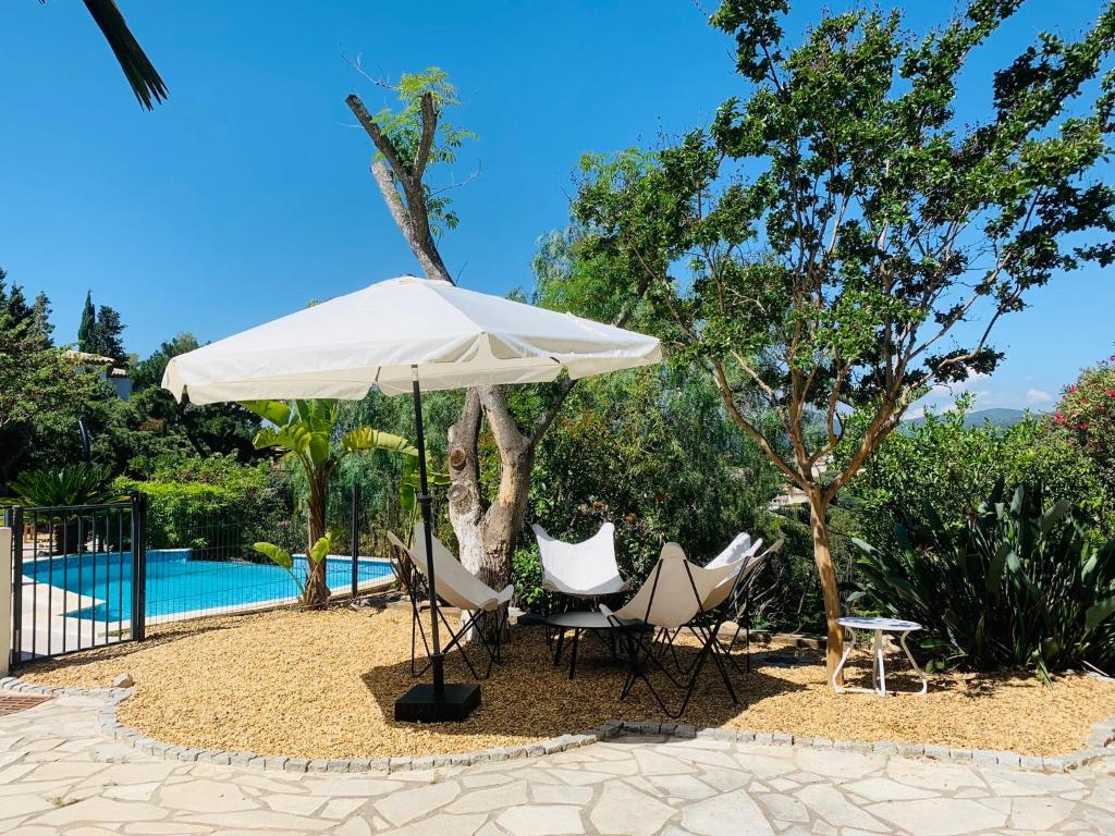 - un parasol blanc et des chaises à côté de la piscine dans l'établissement Maison La Source, à Saint-Peïre-sur-Mer