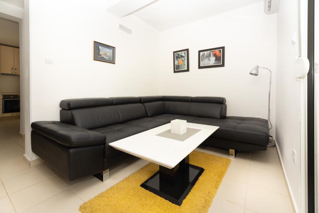 a living room with a black couch and a white table at Apartments Horizont in Budva