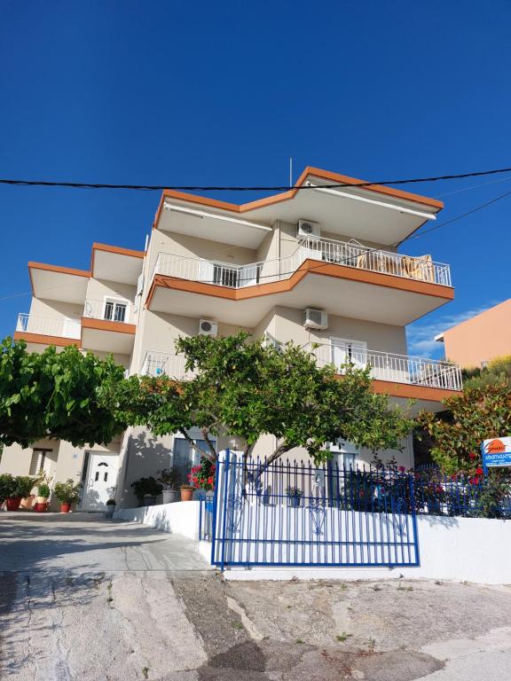 un bâtiment avec une clôture bleue devant lui dans l'établissement Sunset Apartments, à Kanali