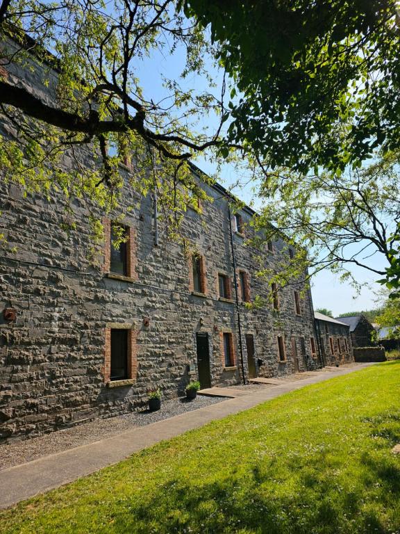 een groot stenen gebouw met een grasveld ervoor bij The Koze in Leitrim