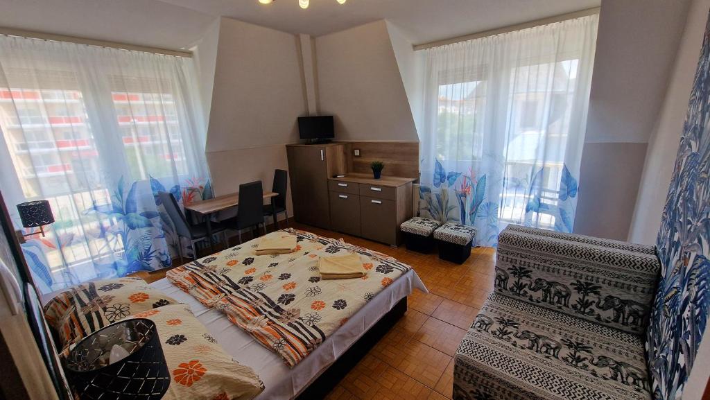 1 dormitorio con 1 cama en una habitación con ventanas en Napsugár Apartmanház, en Siófok