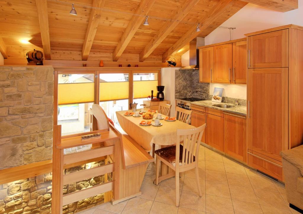 una cocina con armarios de madera y una mesa con sillas. en Ferienwohnung Chalet Püzji, en Zermatt