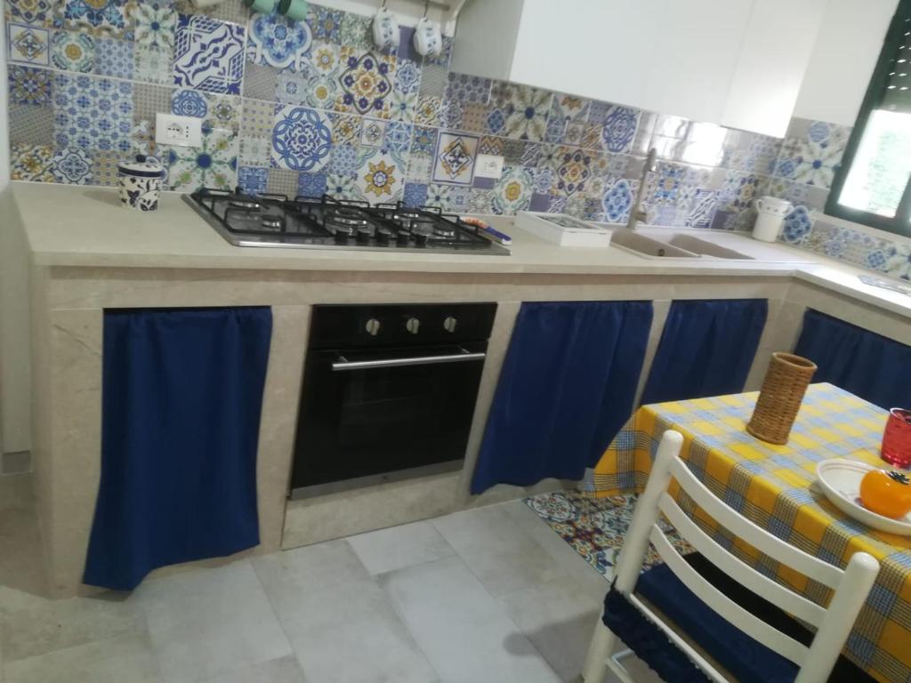 a kitchen with a stove top oven next to a table at Villa Lucia in Santa Maria Del Focallo