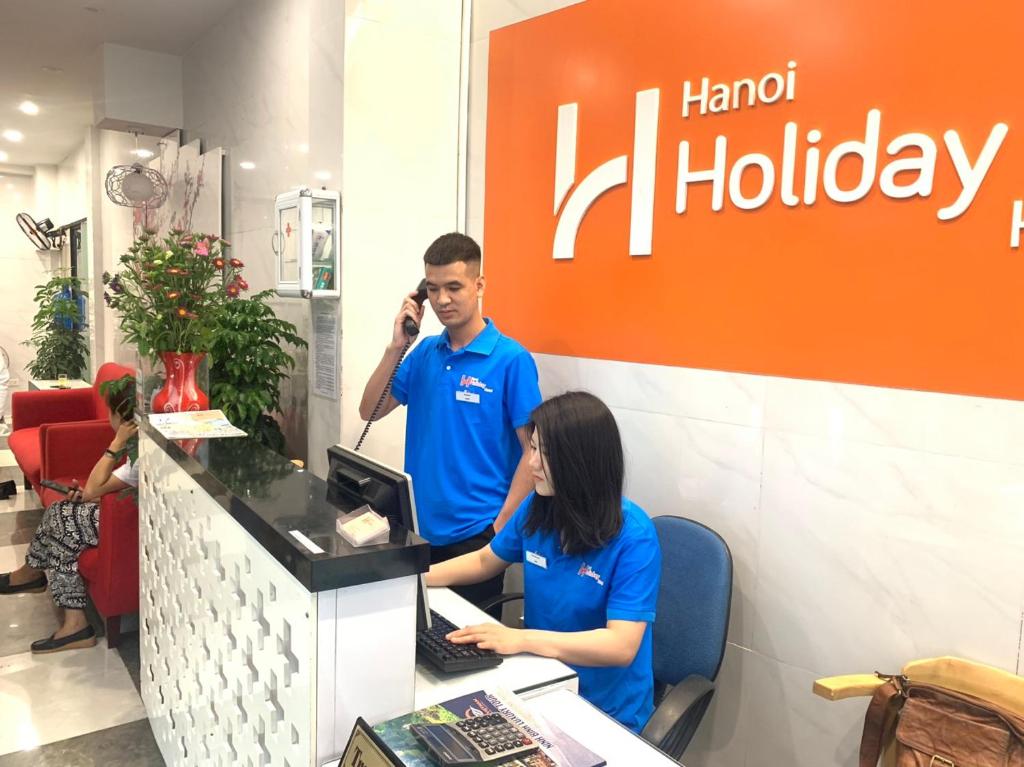a man and a woman sitting at a counter talking on a cell phone at Hanoi Holiday Hotel in Hanoi