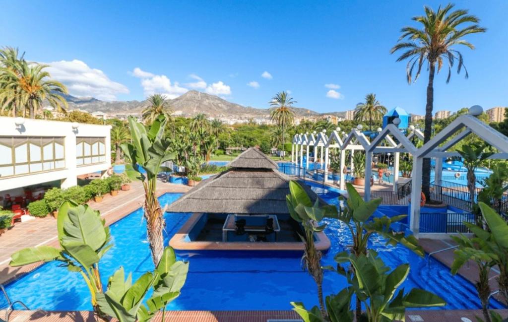 einen Pool in einem Resort mit Palmen und einem Gebäude in der Unterkunft Benalbeach Smart Suite in Benalmádena