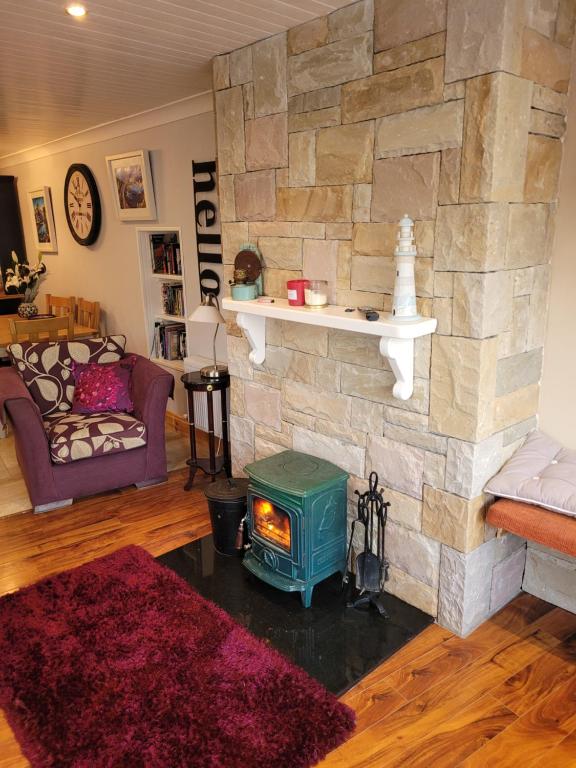 a living room with a stone wall with a stove at Old Bakery Roundstoneselfcatering in Roundstone