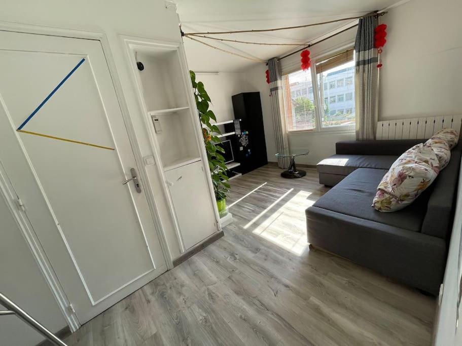 ein Wohnzimmer mit einem Sofa und einer Schiebetür in der Unterkunft Maison de ville,RER A 20 min pour Paris/Disneyland in Neuilly-sur-Marne
