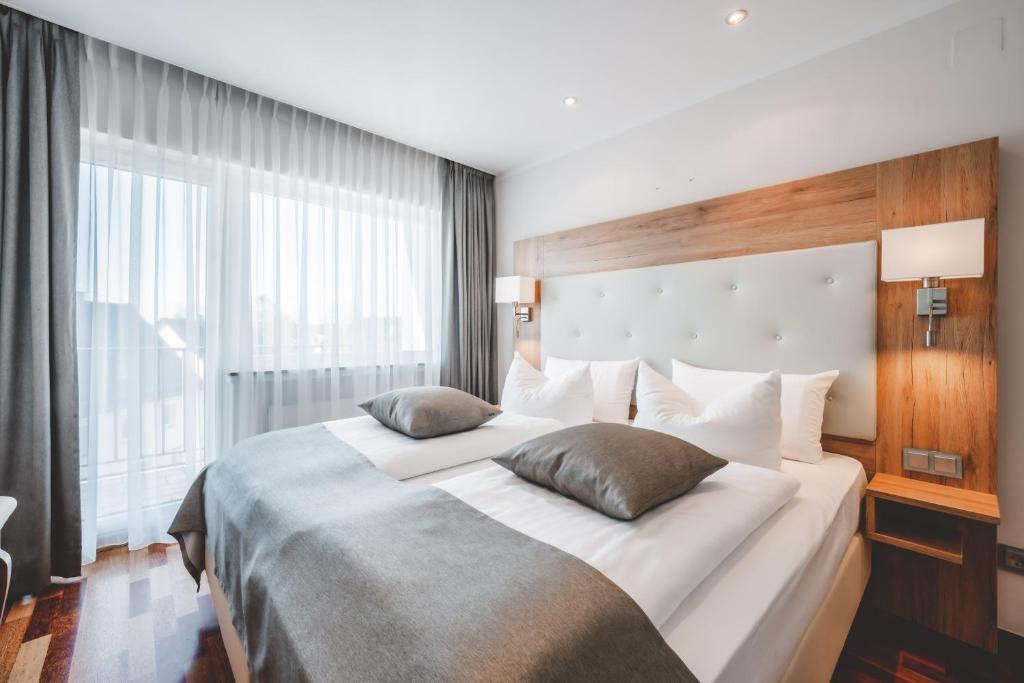 a bedroom with a large bed with a large window at Landidyll Hotel Weidenbrück & SPA in Swisttal