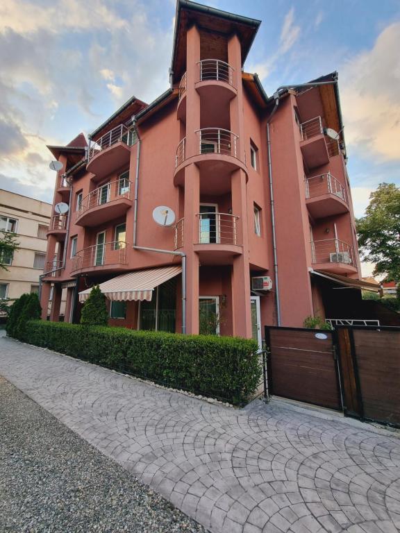 un gran edificio rosa con una valla delante en Бутикови апартаменти Емона, en Ravda