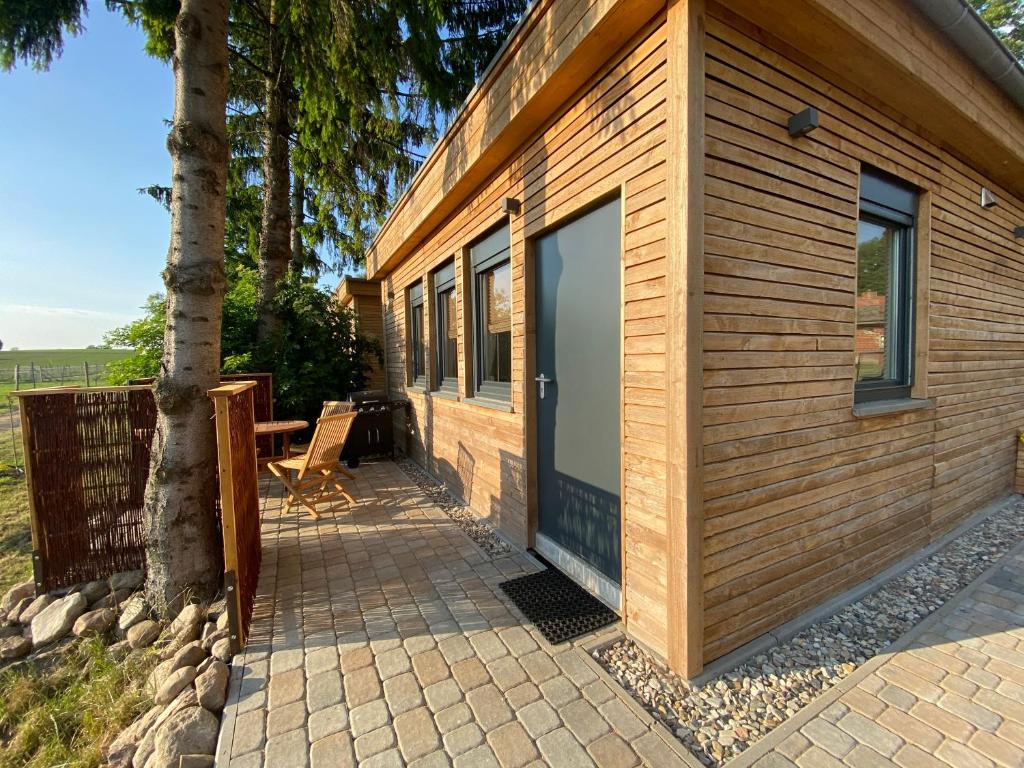 Cabaña de madera con una gran puerta junto a un árbol en Tiny-Haus Straußenblick 1, en Bad Fallingbostel