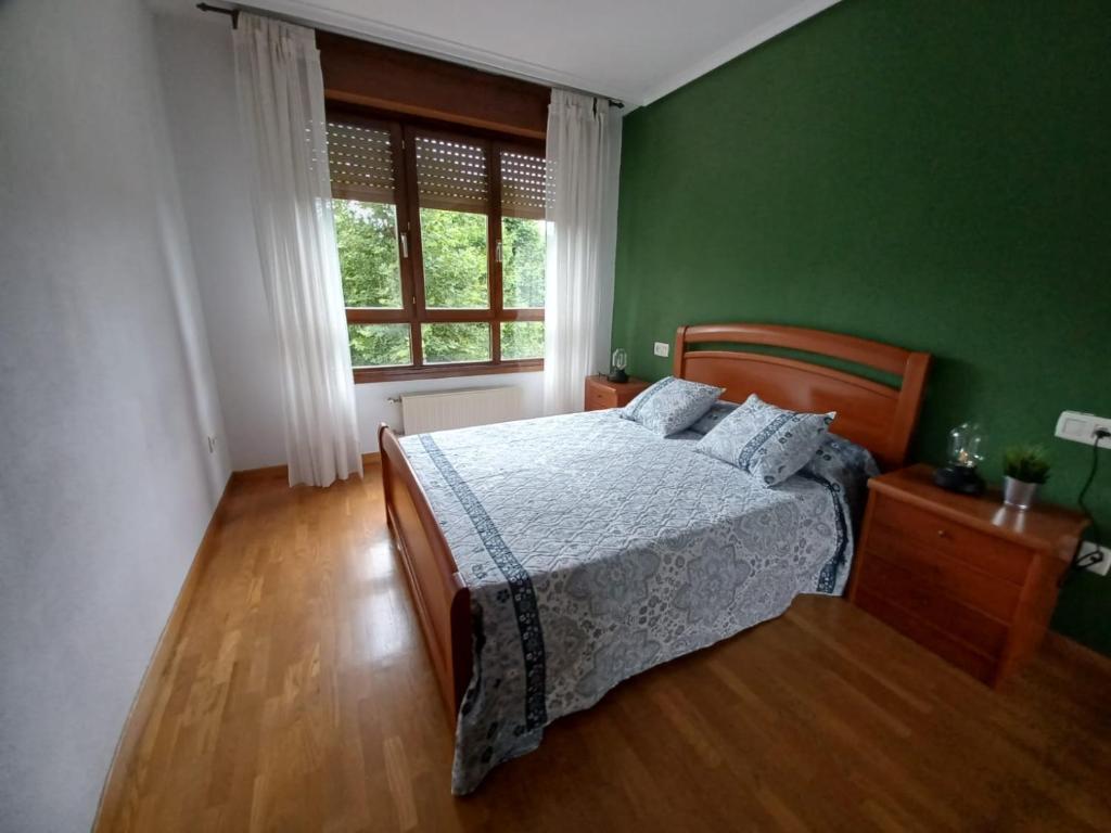 a green bedroom with a bed and a window at Raquel Inn - Garaje incluido in Avilés