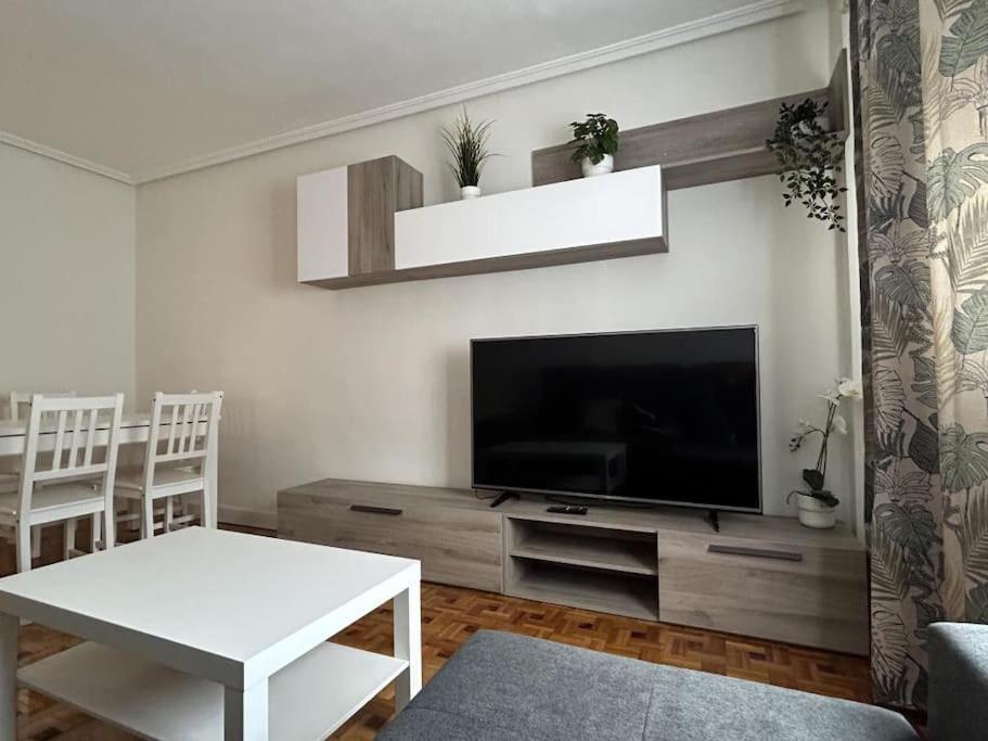 een woonkamer met een televisie en een witte tafel bij La posada de Don Pelayo in Noreña