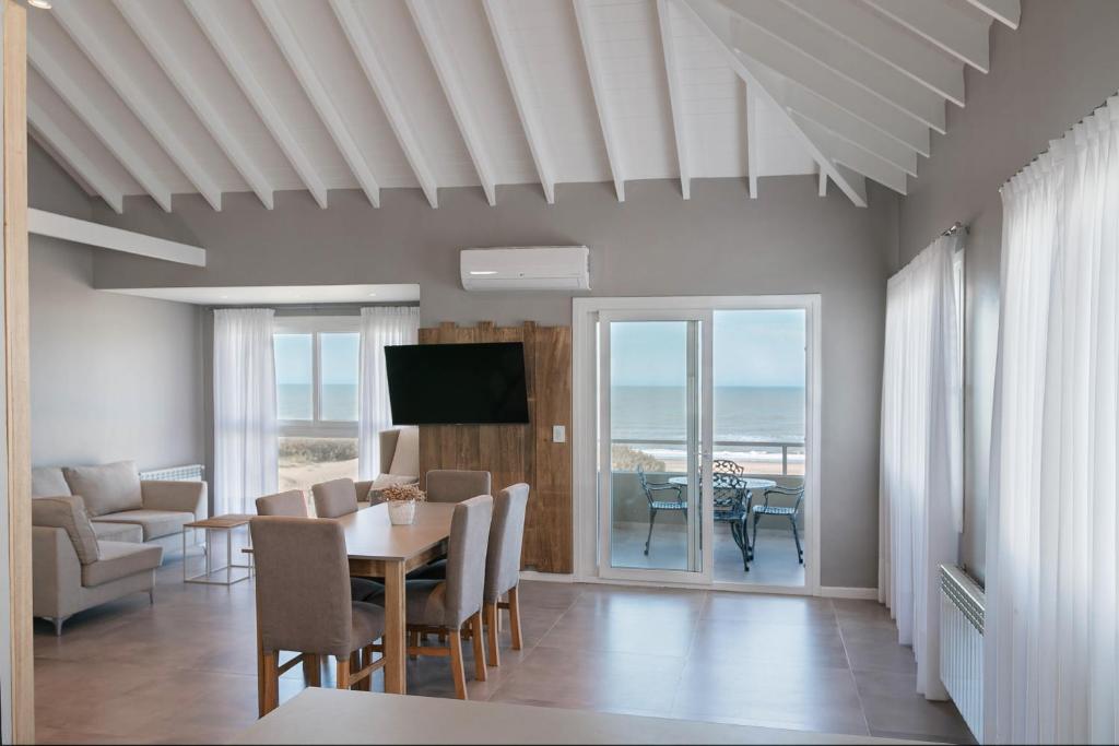 a dining room with a table and chairs and a television at Arenas Cariló by bund in Carilo