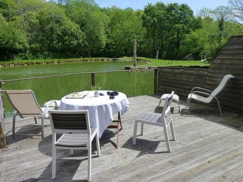 una mesa y sillas en una terraza con vistas a un estanque en La Suite du Pêcheur, balnéo et terrasse privative. Entre terre et mer, en Tréméoc