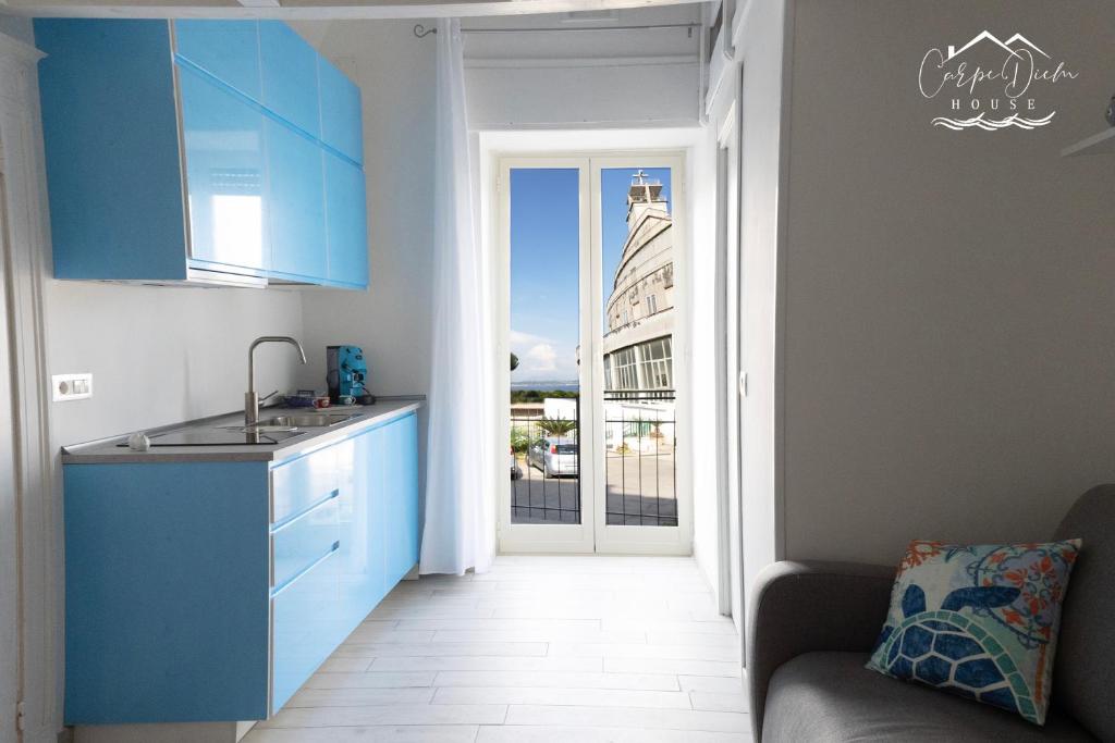uma cozinha com armários azuis e uma porta aberta em Carpe Diem House em Bacoli