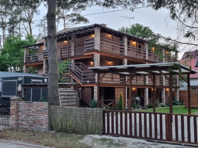 une grande maison en bois avec une clôture devant elle dans l'établissement Pensjonat pod Dębami, à Pobierowo