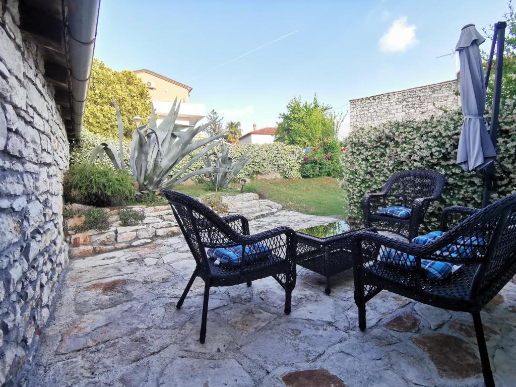 three chairs and an umbrella on a stone patio at Haus Cataleya in Umag