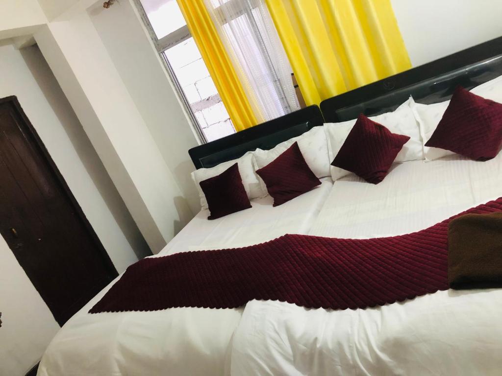 sypialnia z dużym łóżkiem z białymi i czerwonymi poduszkami w obiekcie Darjeeling Homestay w mieście Dardżyling