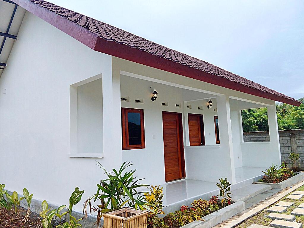 a small white house with a red roof at Singon LOMBOK homestay in Selong Belanak