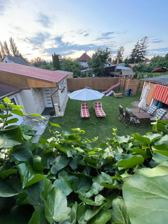 - un jardin avec 2 chaises longues et un parasol dans l'établissement Simply House, à Balatonboglár