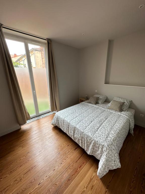 a bedroom with a bed and a large window at *Le Terracotta* T2 Hyper-Centre in Roanne