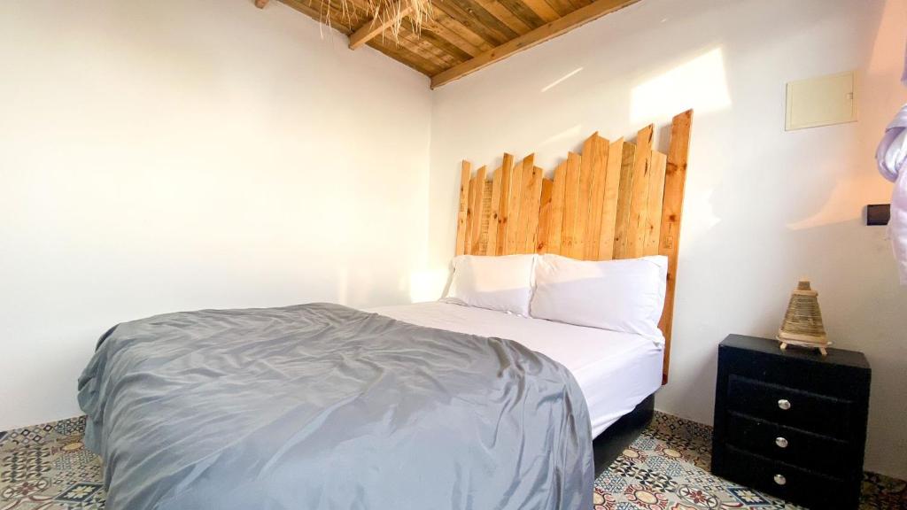 a bedroom with a bed with a wooden headboard at EL Faro Surfstay in Tamri