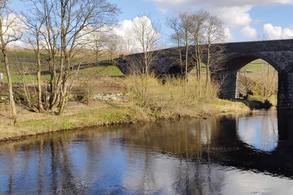 un pont sur une rivière dans un champ dans l'établissement Riverside Cottage, Helwith Bridge, Yorkshire Dales, à Horton in Ribblesdale
