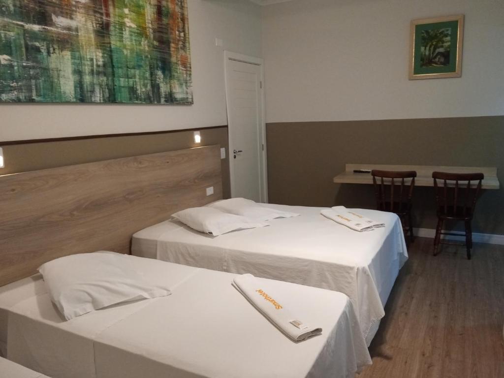 a hotel room with two beds and a table at Smart Hotel in Registro