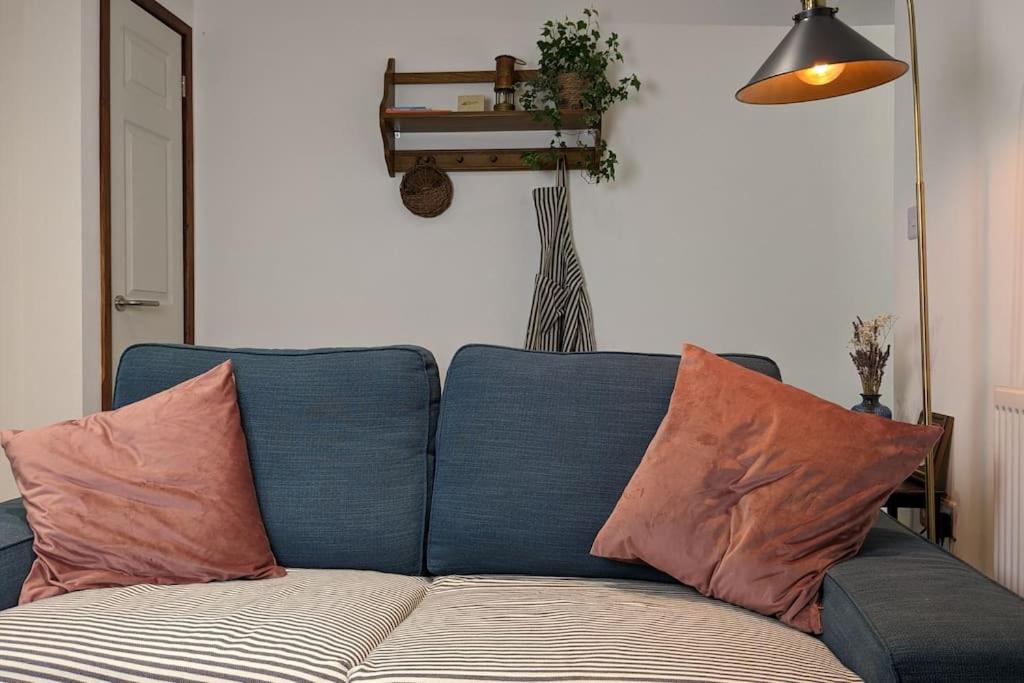 un sofá azul con almohadas en la sala de estar en Rustic Vintage Cottage: Near Waterfall Country, en Pont-Nedd-Fechan