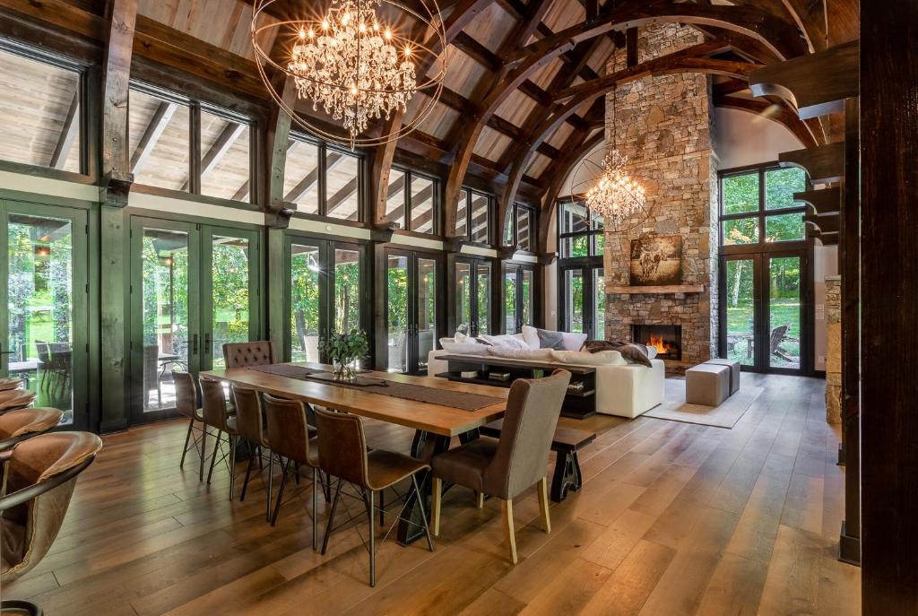 uma sala de estar em plano aberto com uma mesa de jantar e uma lareira em Modern Mountain Creekhouse em Maggie Valley