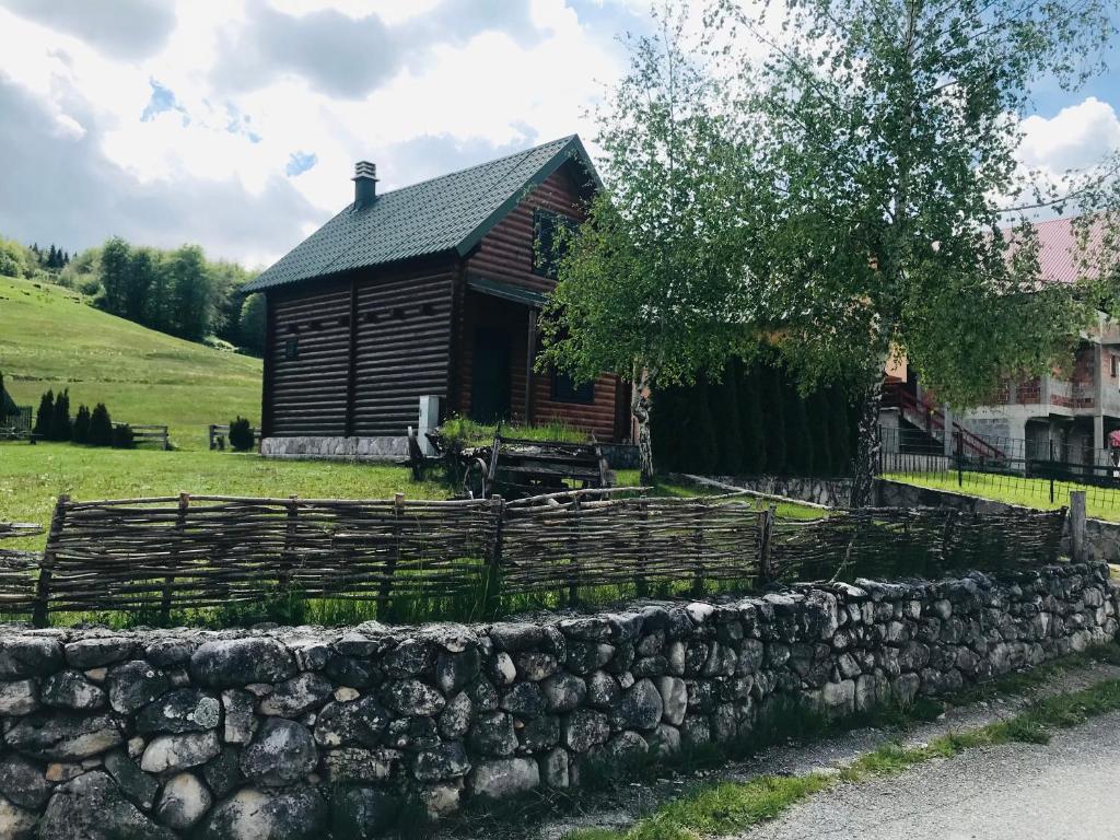 una cabaña de madera con una pared de piedra delante de ella en Anja rent house en Žabljak