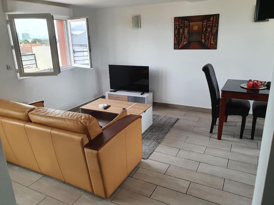 ein Wohnzimmer mit einem Sofa und einem Tisch in der Unterkunft Beau duplex dans une résidence calme in Romainville