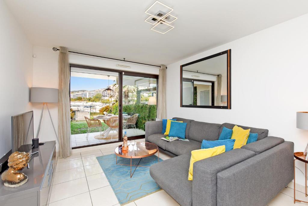 a living room with a couch and a table at Luxury Garden apartment with stunning Cannes Marina views in Mandelieu-la-Napoule