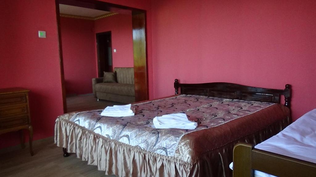 1 dormitorio con 1 cama con paredes rojas y espejo en Вила Верона, en Kavarna