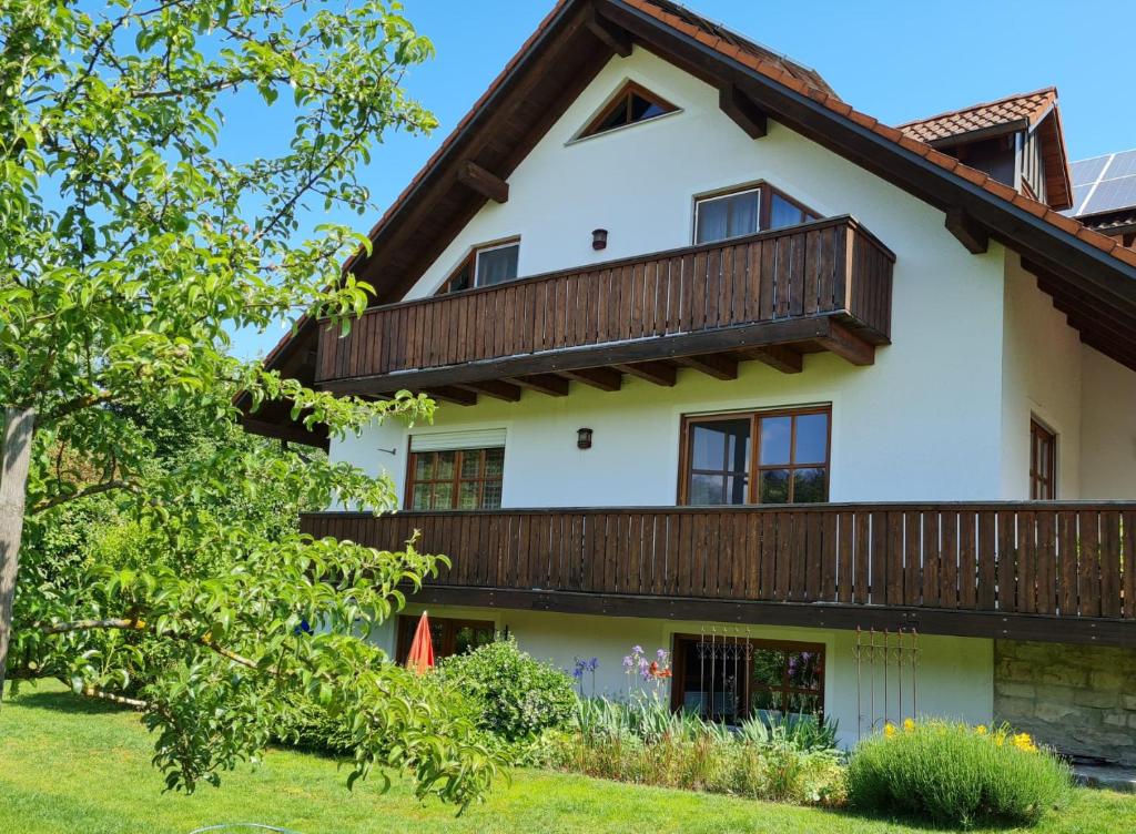 uma grande casa branca com uma varanda de madeira em Altmühltaler Ferienwohnung em Beilngries