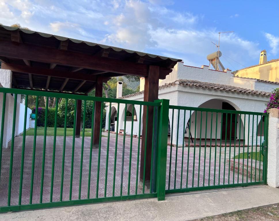 ein grüner Zaun mit einem Tor vor einem Gebäude in der Unterkunft La Babbaiola di Torre delle Stelle in Torre delle Stelle