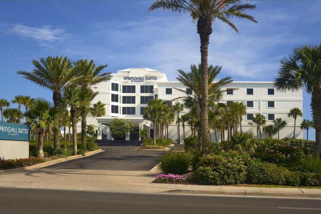 SpringHill Suites by Marriott Pensacola Beach في شاطئ بينساكولا: مبنى ابيض فيه نخيل وشارع