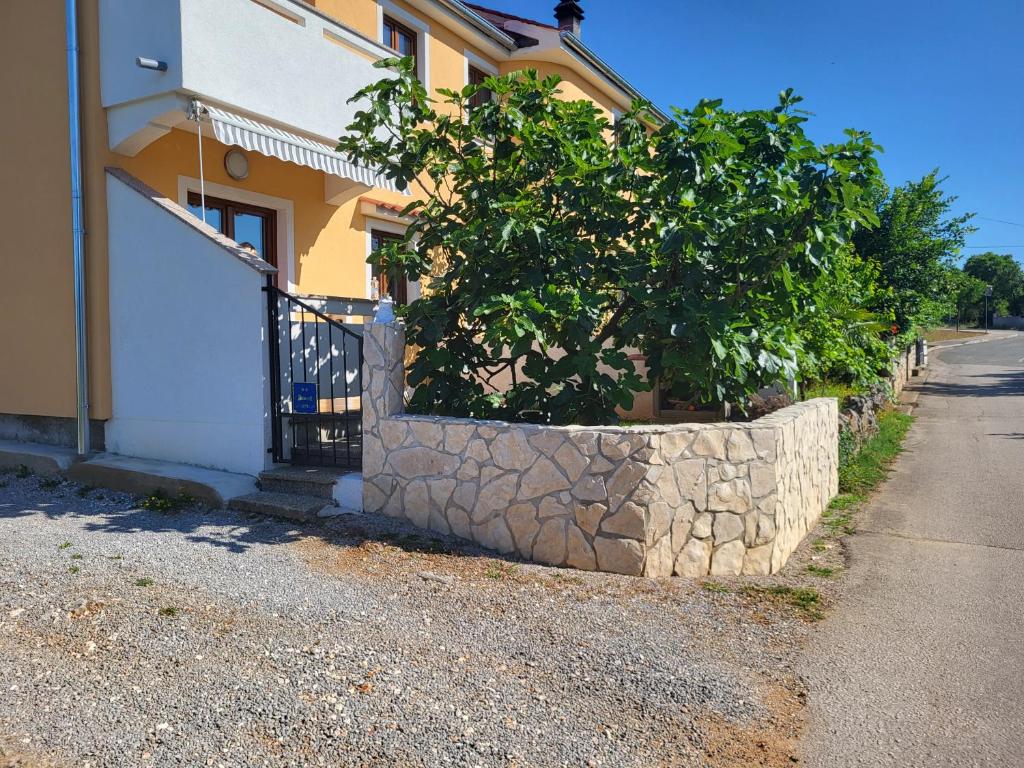 a tree in a stone planter next to a building at Apartment Luna in Malinska